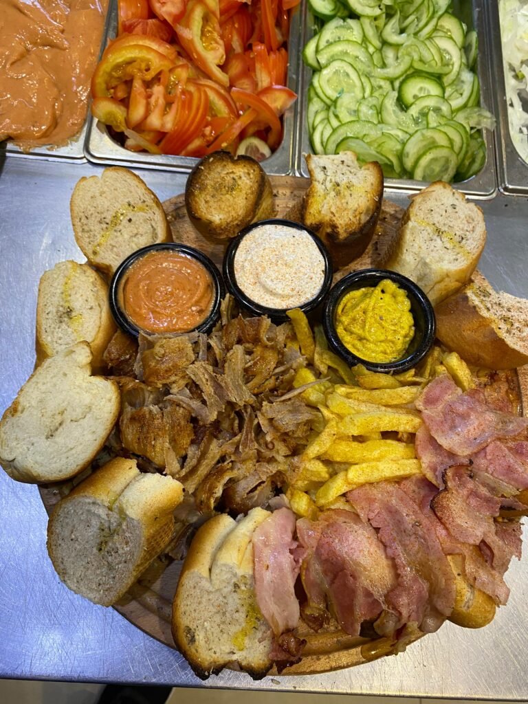 View of an open plate gyro and bacon portion, with chips, bread and sauces at fast food 3 Fiori Vlore