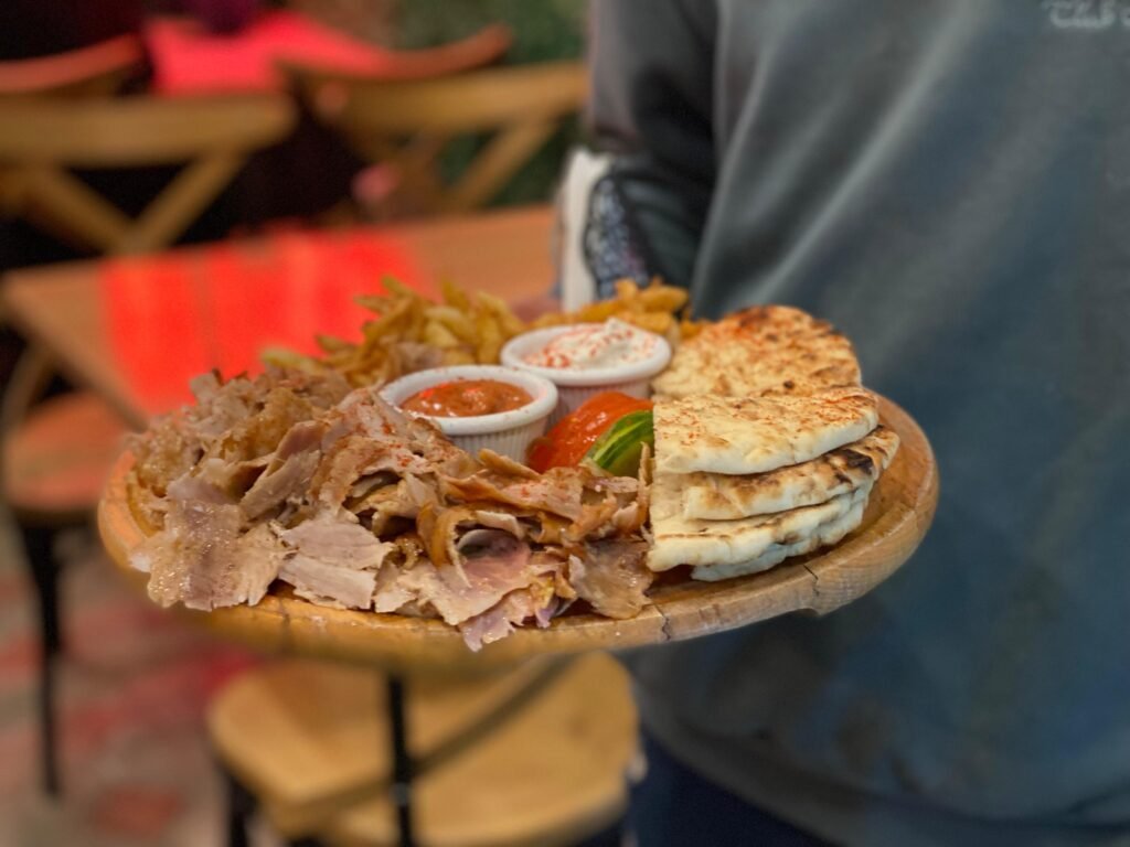 A waiter holding an open portion plate of gyro pita at 3 Fiori Fast Food Vlore