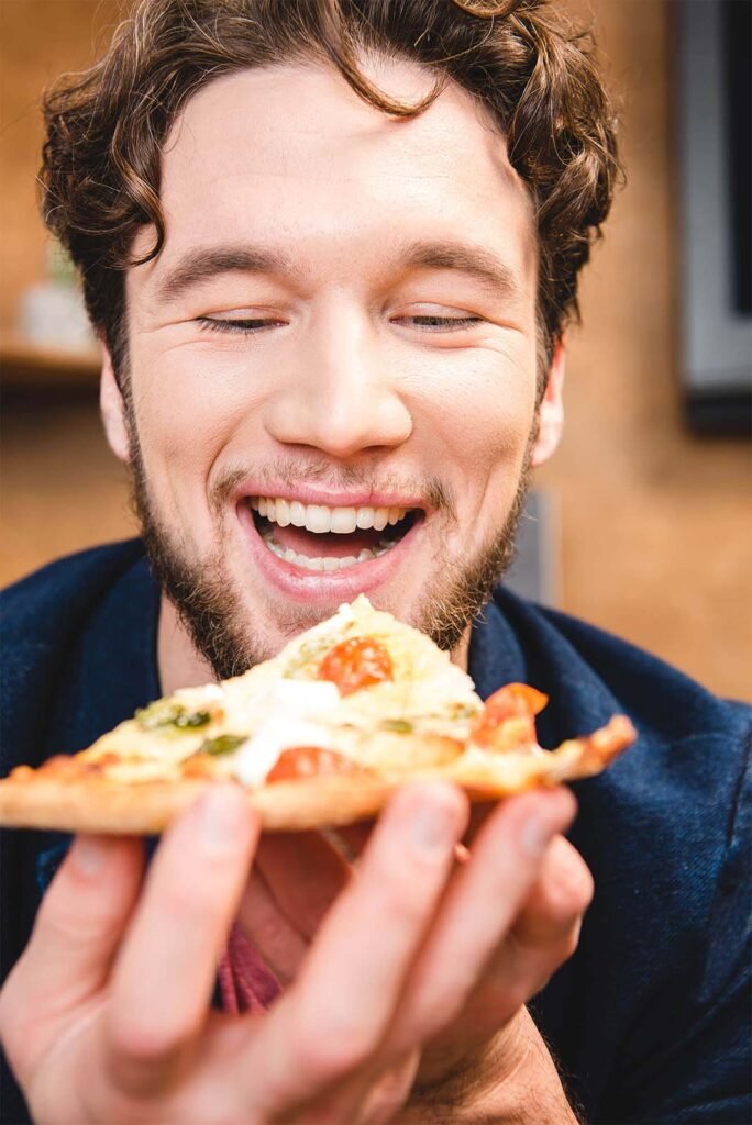 Close up view of a happy man eating a pizza